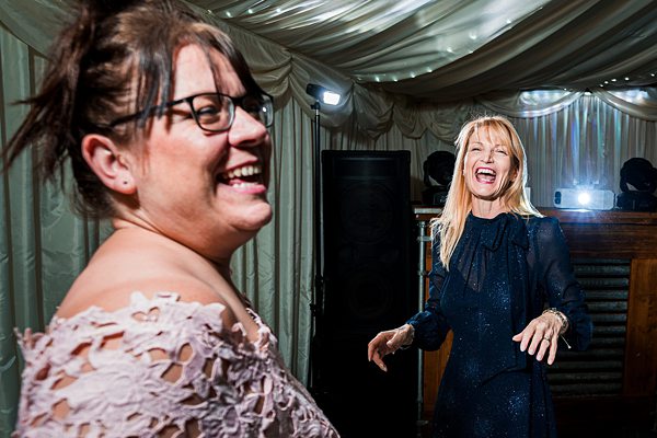 Two women laughing and dancing at a party.