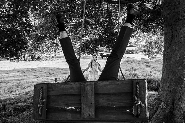 Man upside down on swing, woman laughing.