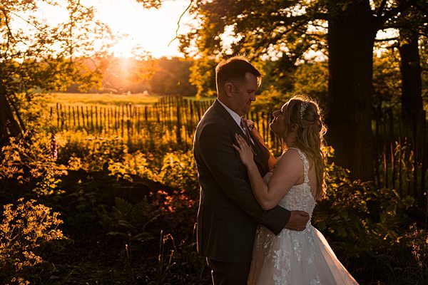 Couple embraces at sunset in a garden.