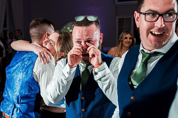 Men celebrating joyfully at a wedding reception.