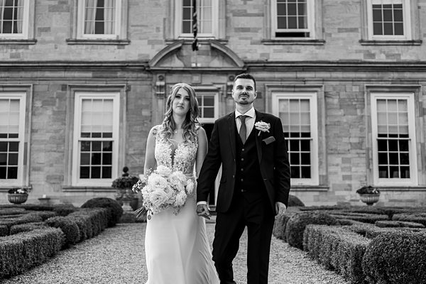Bride and groom walking outside historic building.