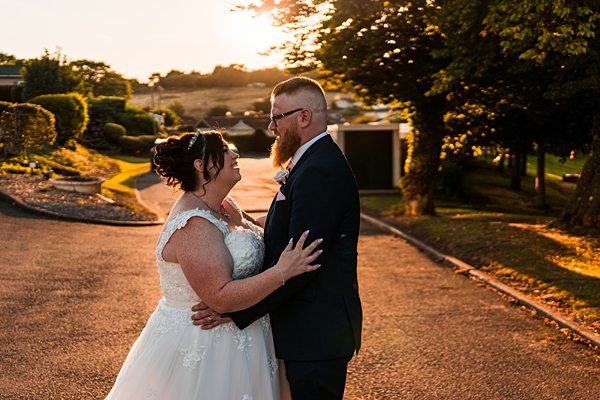 Bride and groom smiling at sunset wedding