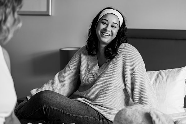 Woman smiling while sitting on a bed.