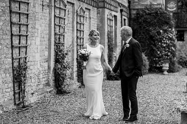 Couple holding hands on wedding day outside building.
