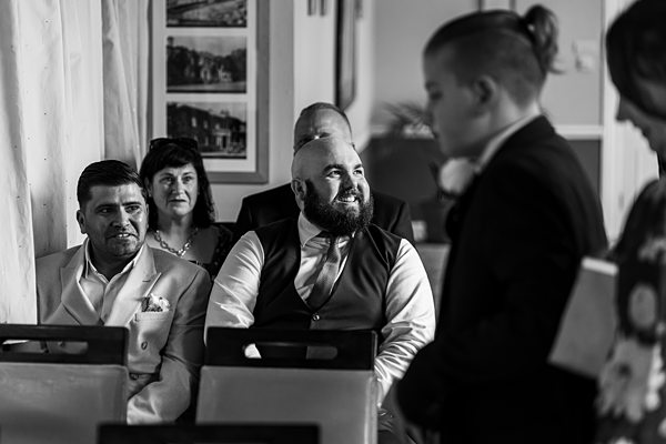 People smiling at a wedding ceremony indoors.