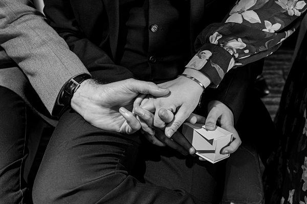 Hands holding, displaying an engagement ring box.