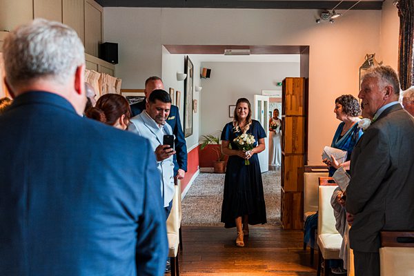 Bridesmaid walks down the aisle at wedding ceremony.