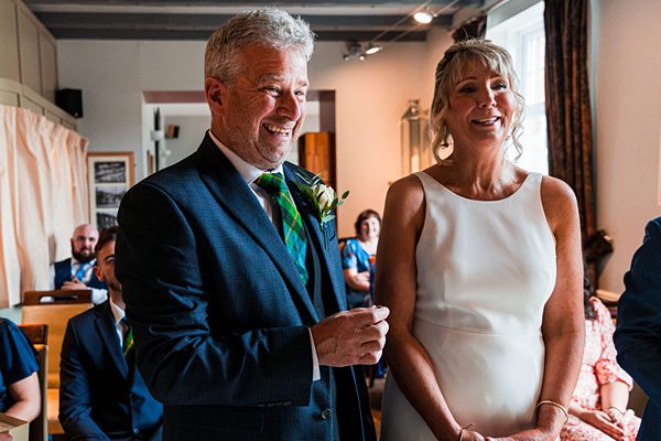 Couple smiling during wedding ceremony in a room.