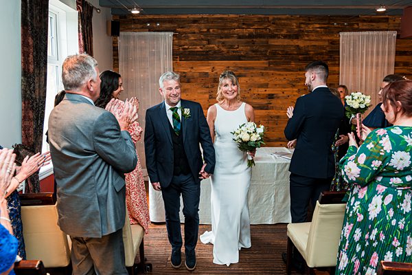 Bride and groom walking down the aisle, smiling.