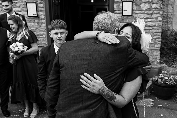 People hugging and smiling at a wedding.