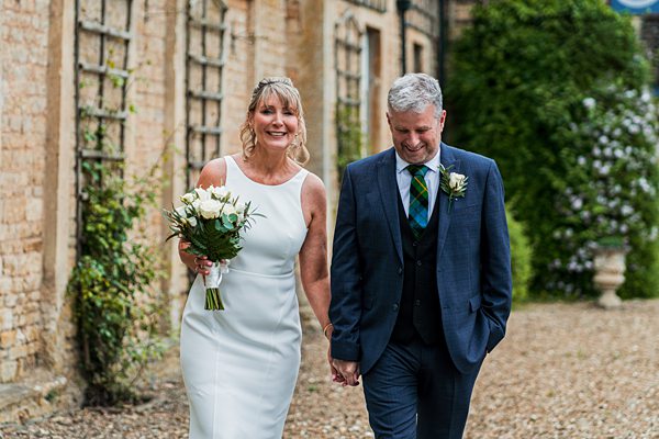 Smiling couple walking outside on wedding day.