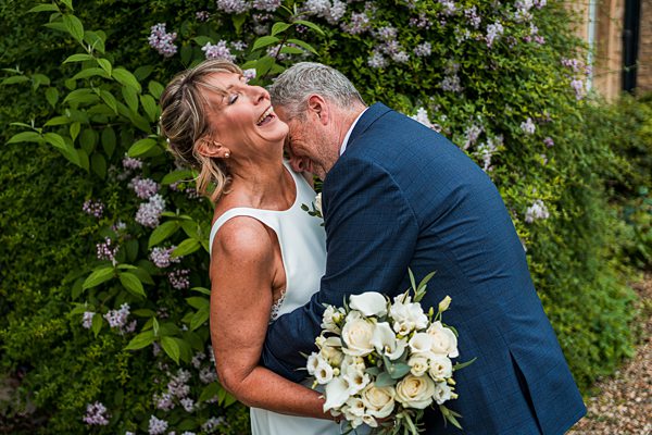 Laughing couple embracing with white roses bouquet.