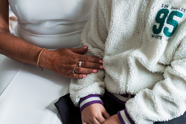 Woman's hand on child's fleece jacket.