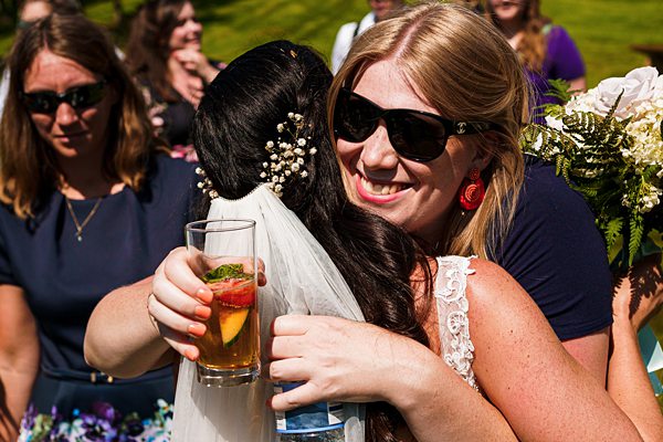 Women hugging at outdoor wedding celebration.