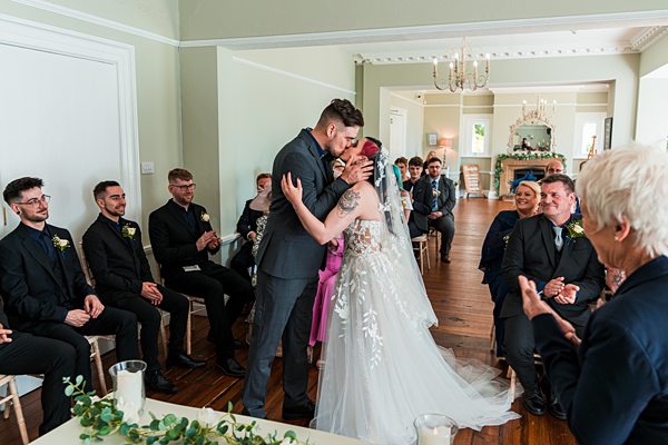 Bride and groom kiss at wedding ceremony indoors