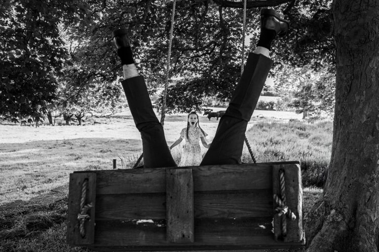Man upside down on swing, surprised woman watching.