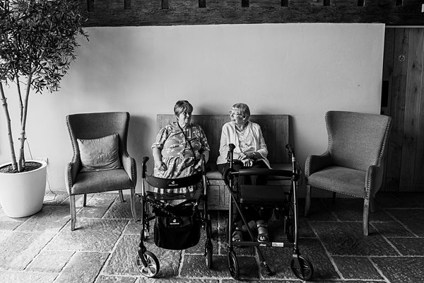 Elderly women sitting with walkers, enjoying conversation.