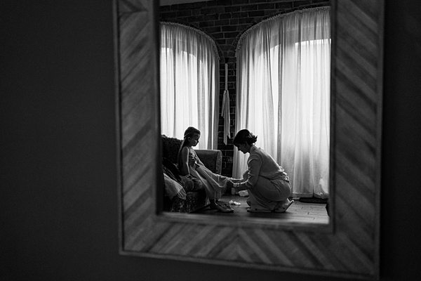 Person helping child with shoes in framed reflection.