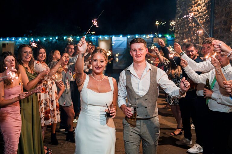 Wedding guests holding sparklers celebrating at night.