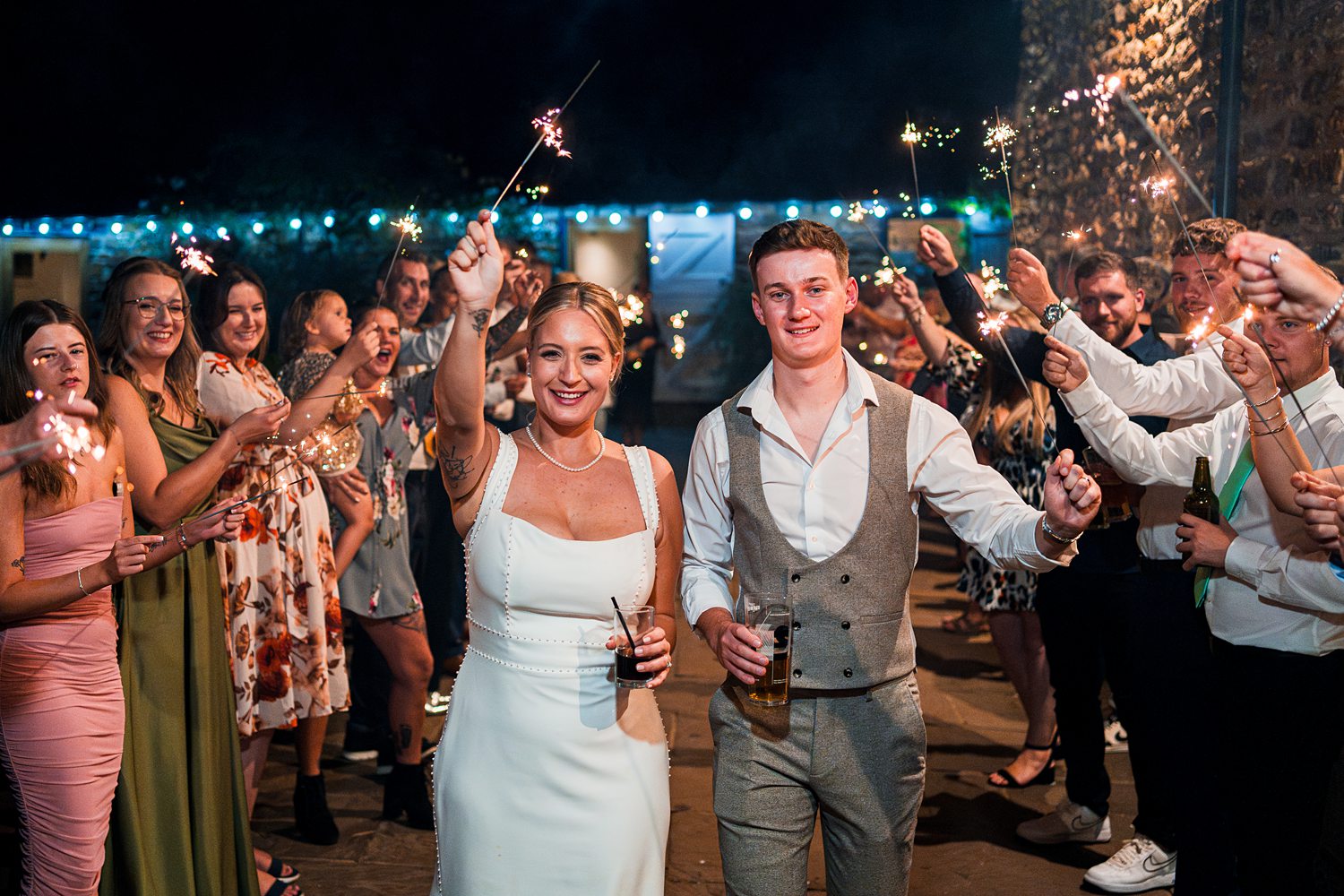 Wedding guests holding sparklers celebrating at night.