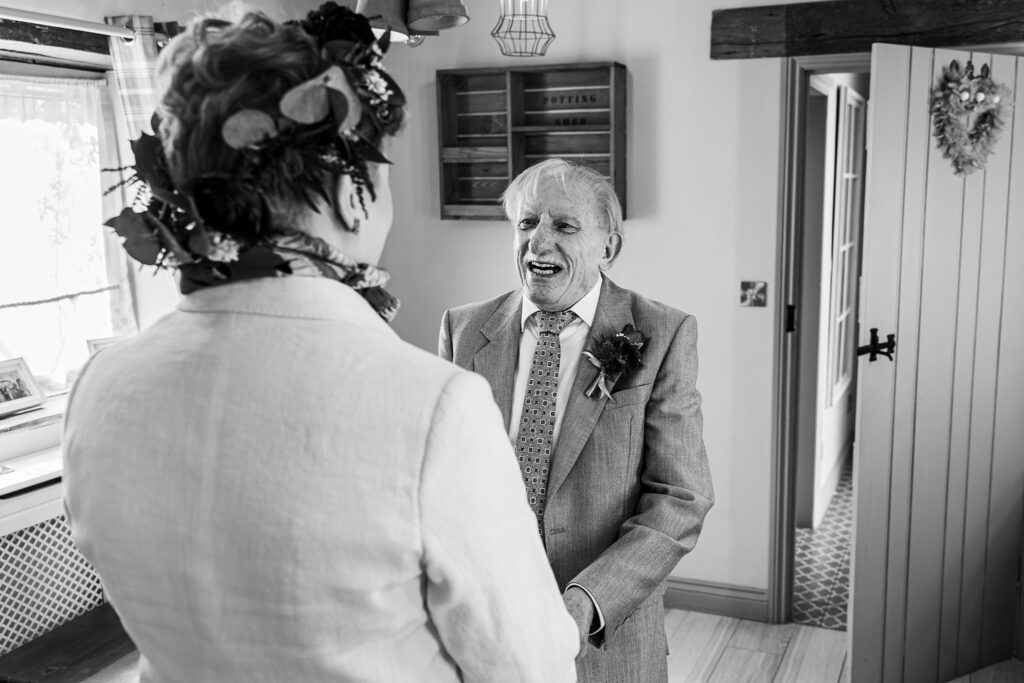 Smiling elderly man in suit with boutonniere indoors.