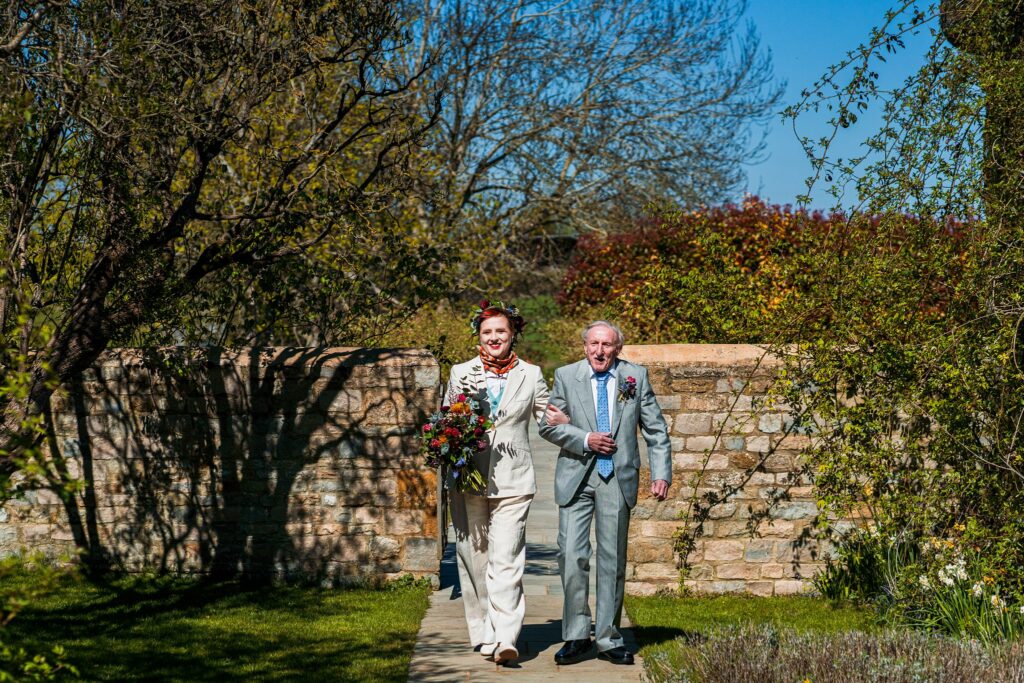 Bride and father walking in garden