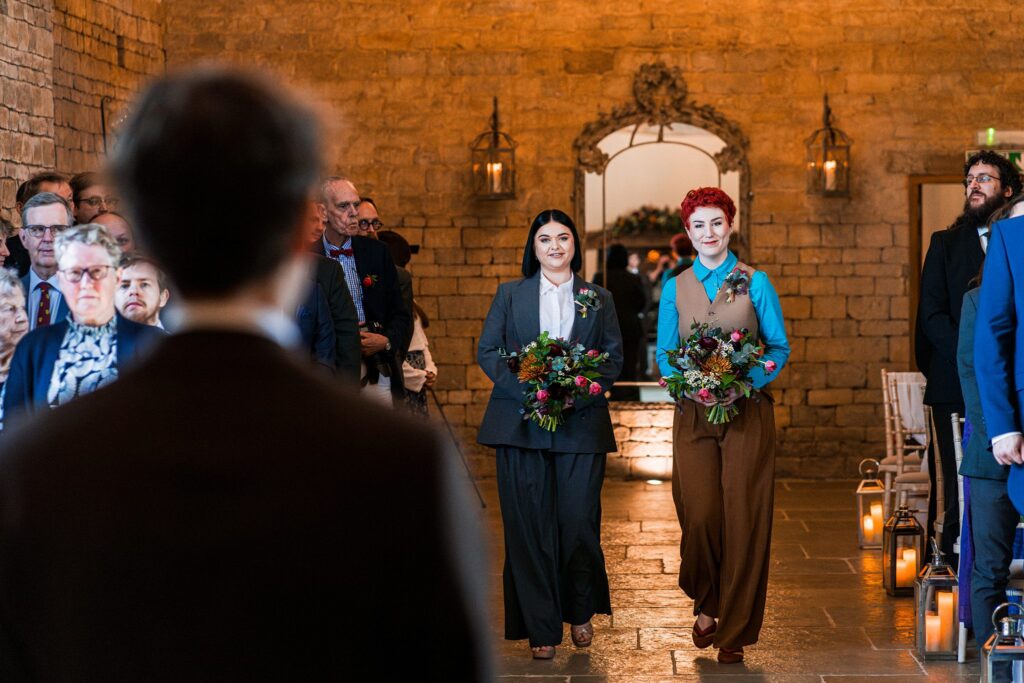Two people walking down wedding aisle with flowers.