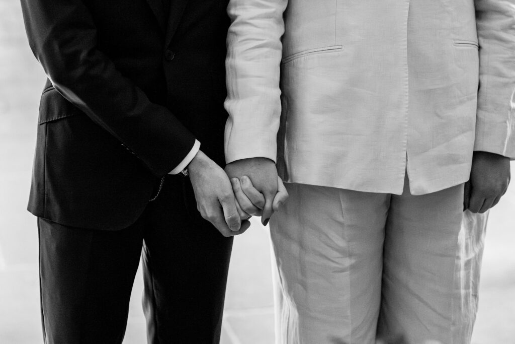 Two people in suits holding hands, close-up.