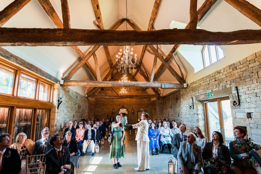 Wedding ceremony in rustic barn with guests seated.