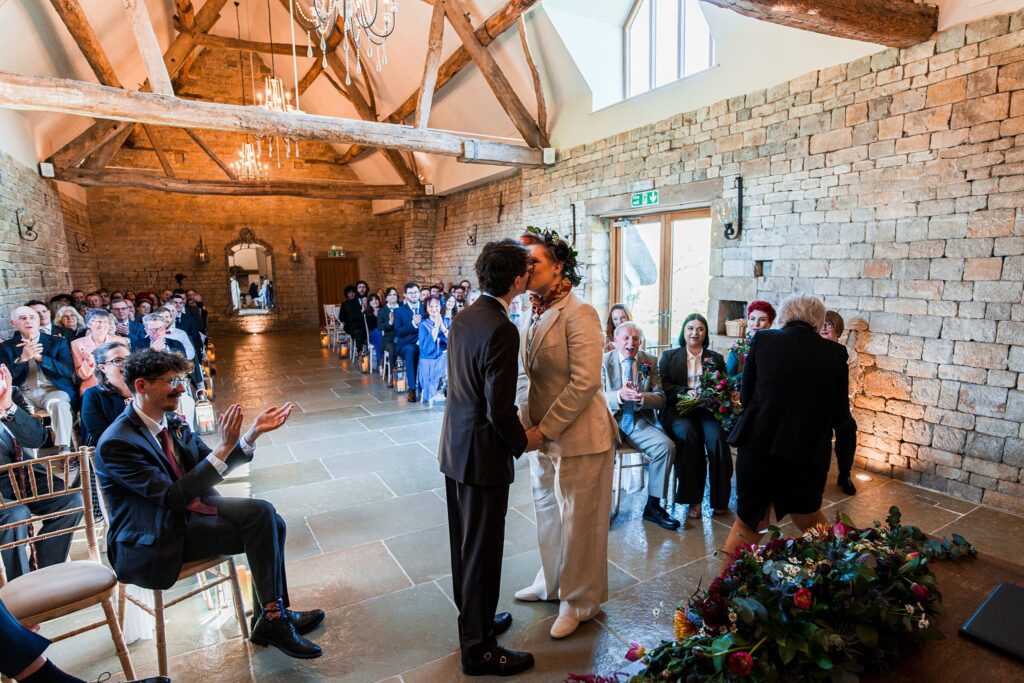 Couple kissing at wedding ceremony in rustic venue.