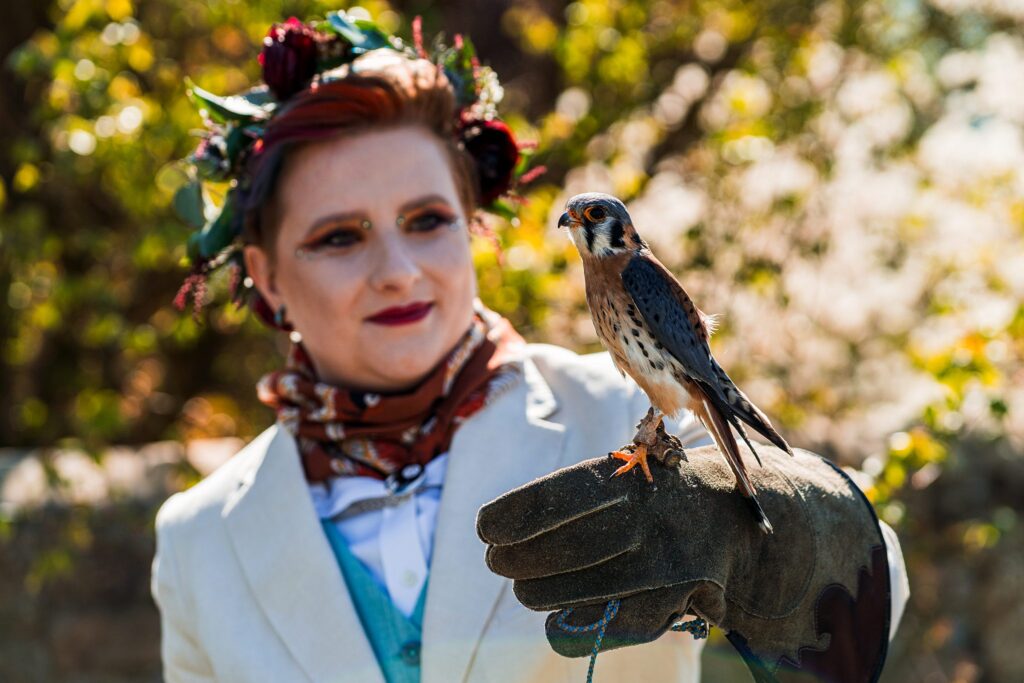 Person holding falcon in garden setting.