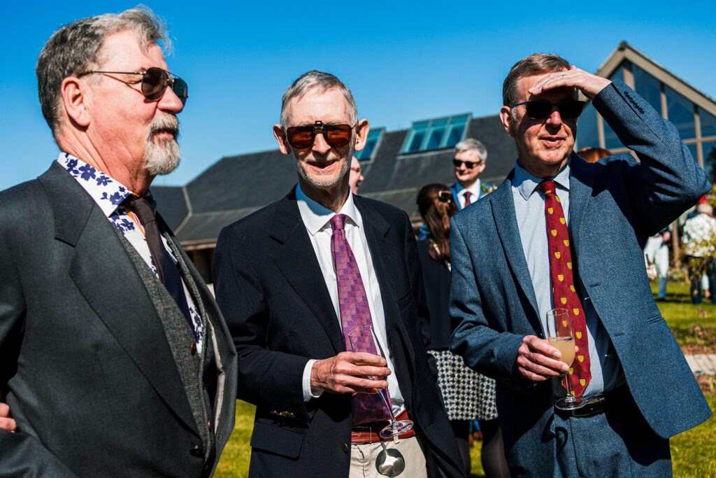 Three men in suits at outdoor event.