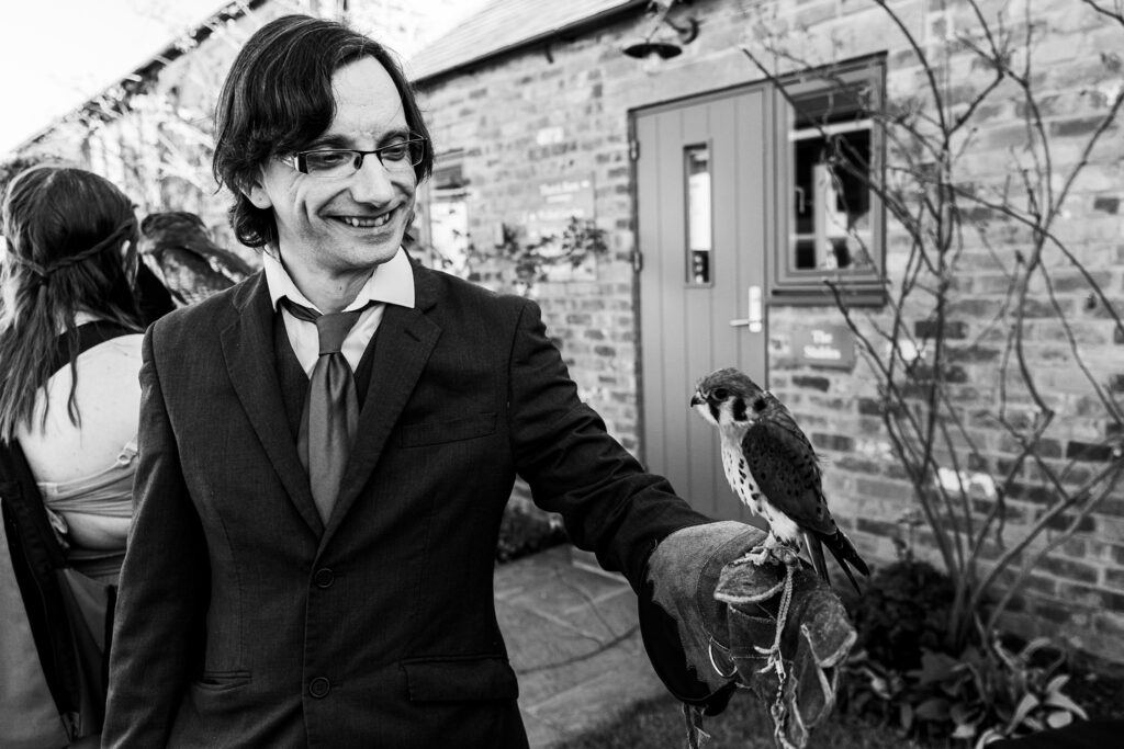 Man holding a falcon in garden ceremony.