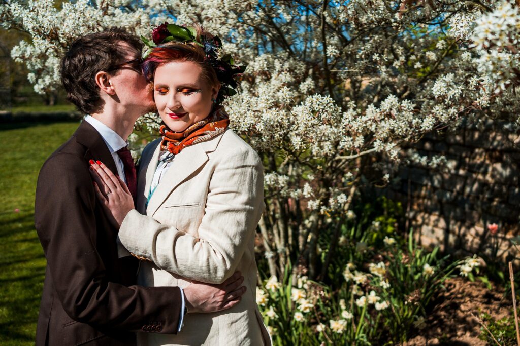 Couple embracing under blooming tree in garden.