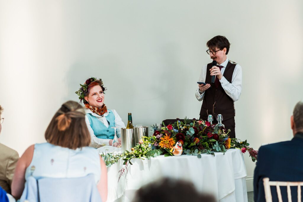 Wedding speech with guests seated, decorated table.