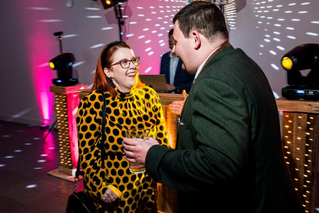 People socialising at party with vibrant lights.