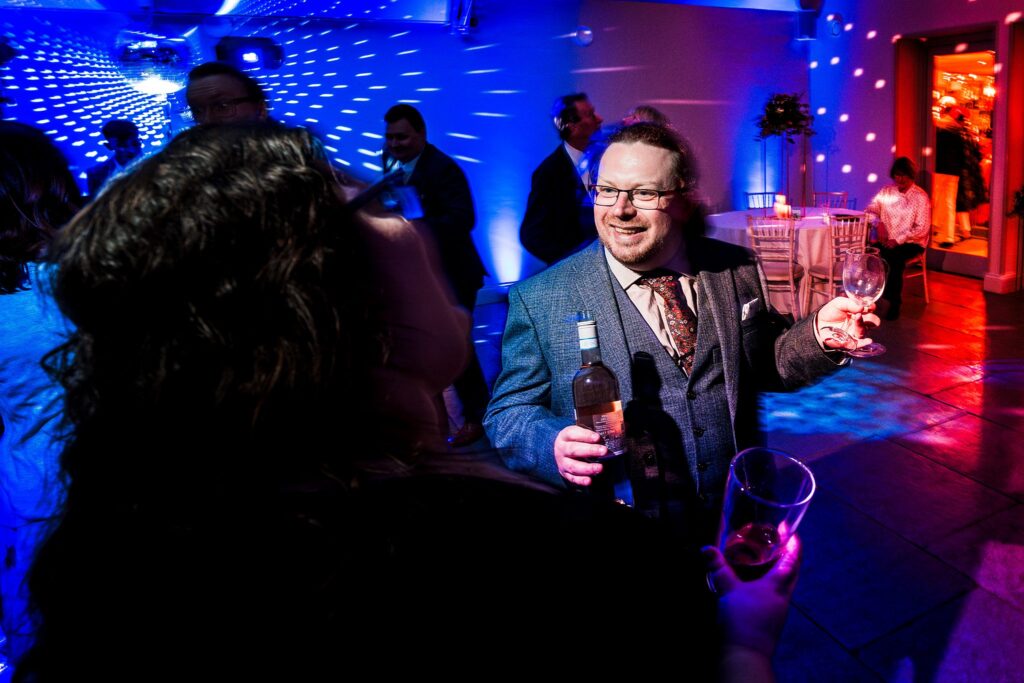 Man celebrating with wine at party.