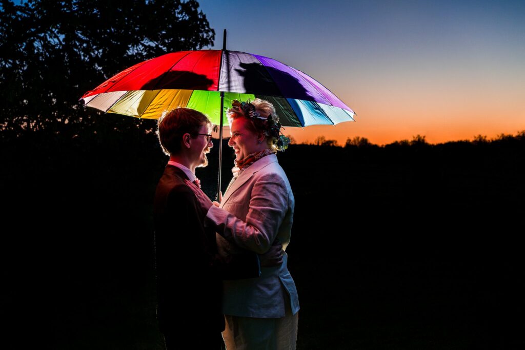 Couple under rainbow umbrella at sunset