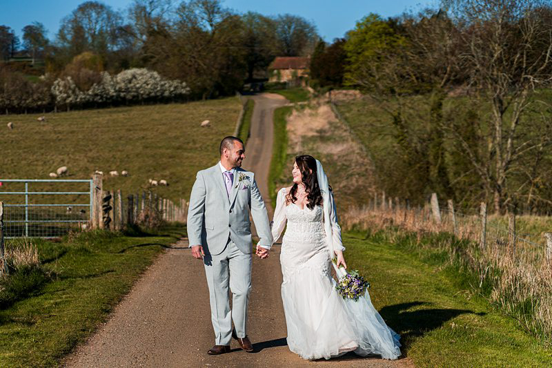 Bride and groom walk in countryside lane